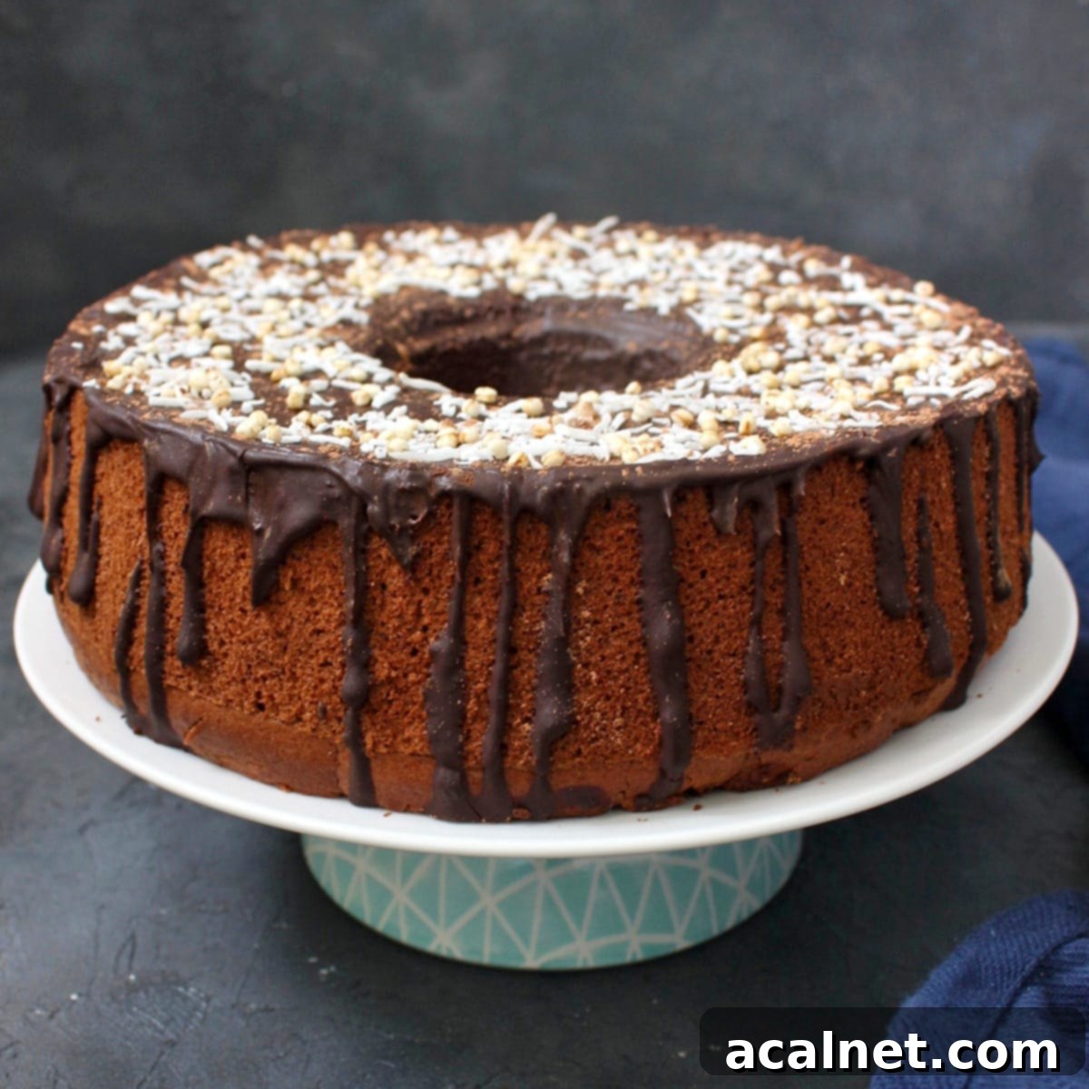 A beautifully decorated Chocolate Chiffon Cake presented on an elegant white and blue cake stand, showcasing its inviting layers and luscious ganache.