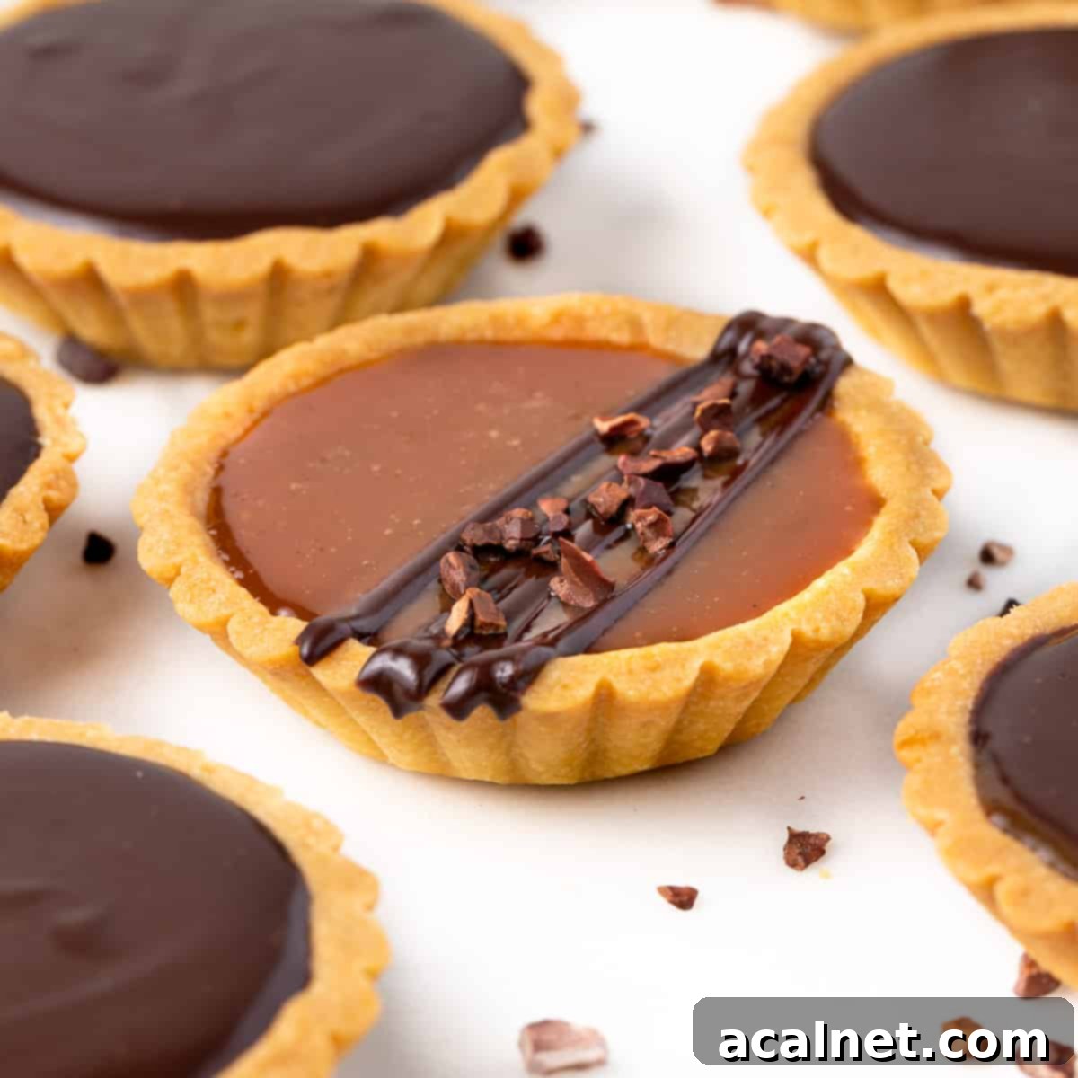 Close up on a caramel tart drizzles with chocolate.