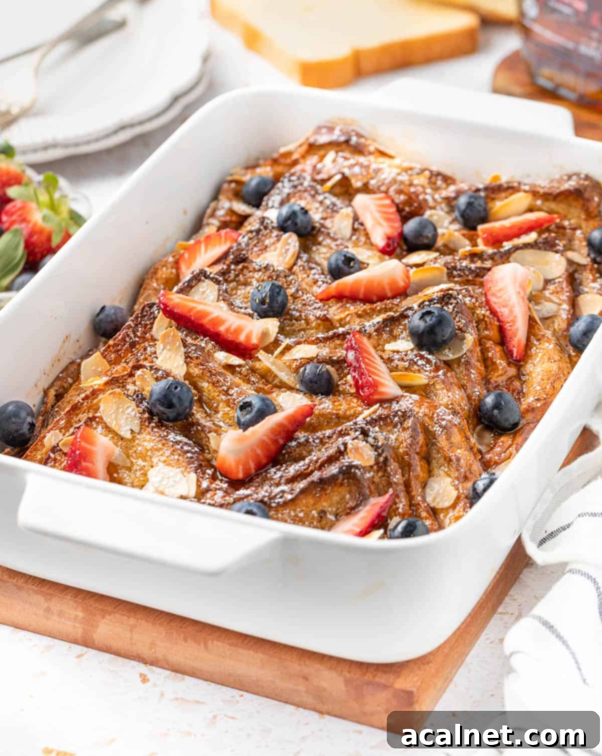 Brioche French Toast Bake 6 French toast bake in a white ceramic baking dish over a wooden cutting board, ready to be served.