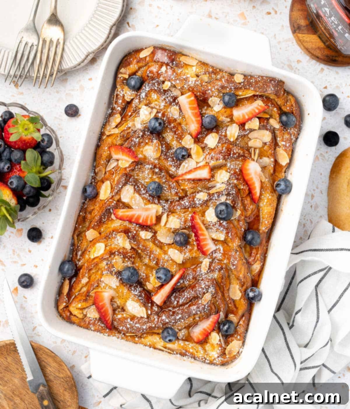 Brioche French Toast Bake 7 Casserole dish seen from above topped with fresh berries, powdered sugar, and a hint of maple syrup.
