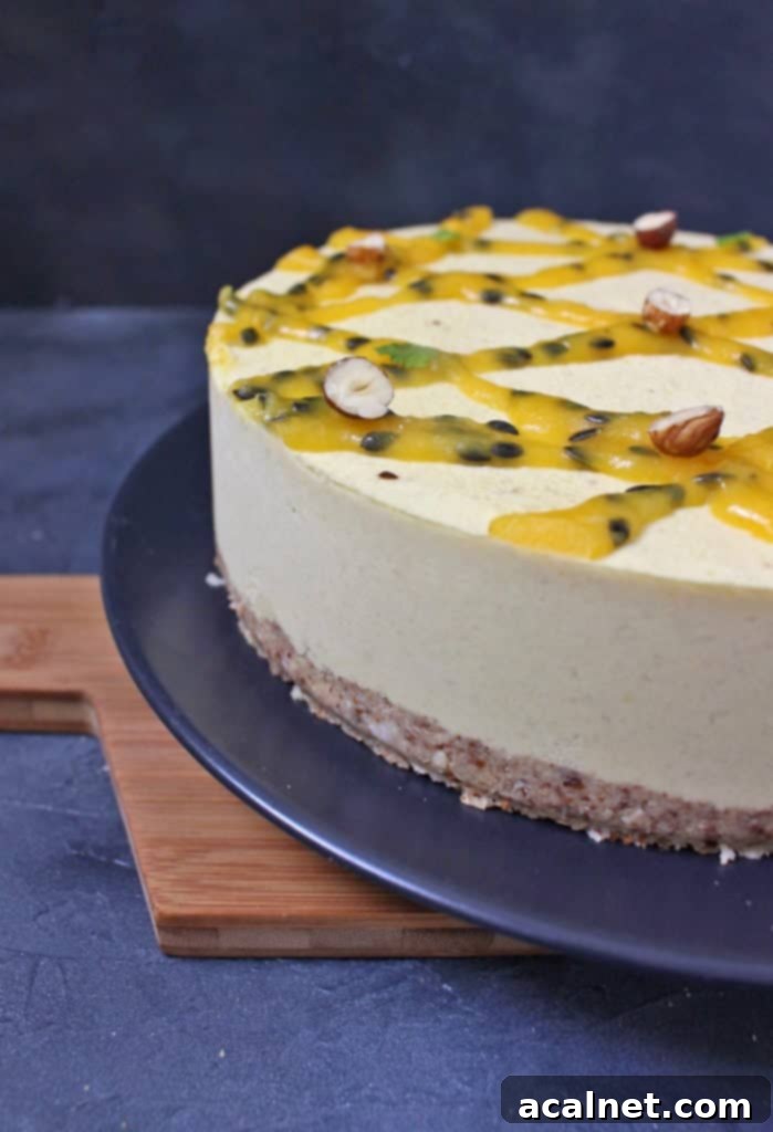 Vegan No-Bake Mango Cheesecake 6 Side view on the Cake on a black plate over a wooden serving board, showcasing the layers and fresh toppings