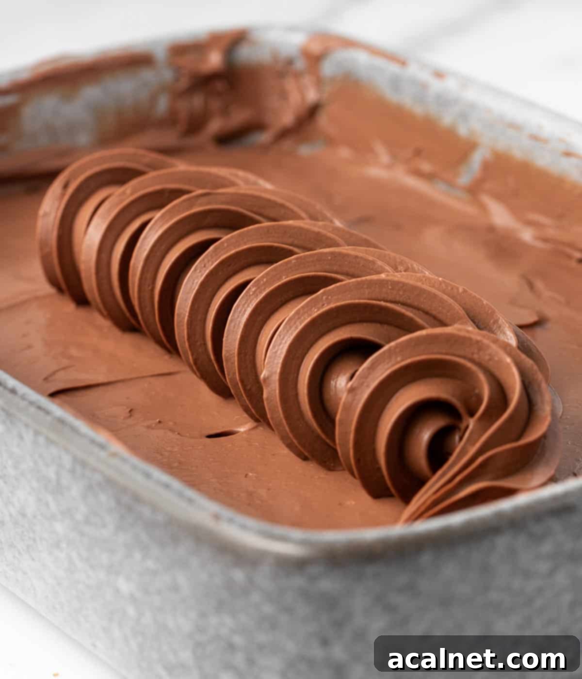 Row of piped namelaka over a layer of cream in a small grey dish.