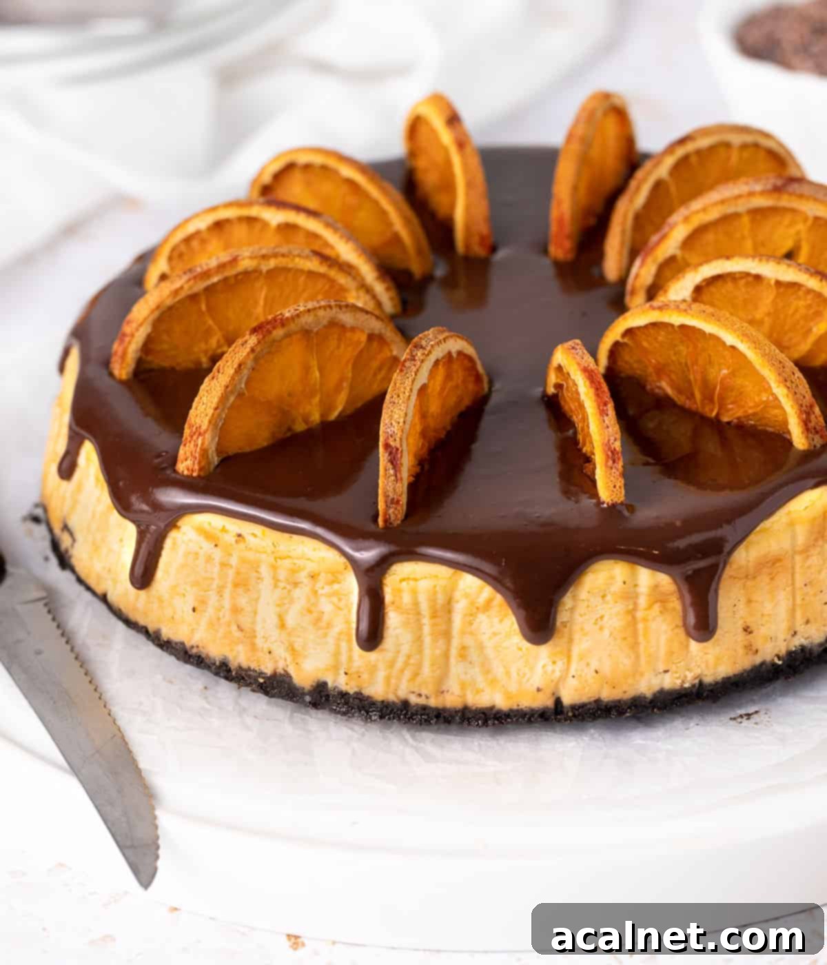 A stunning side view of the chocolate orange cheesecake, with a close-up focus on the rich dark chocolate ganache artfully dripping down the sides of the cake, emphasizing its decadent layers.