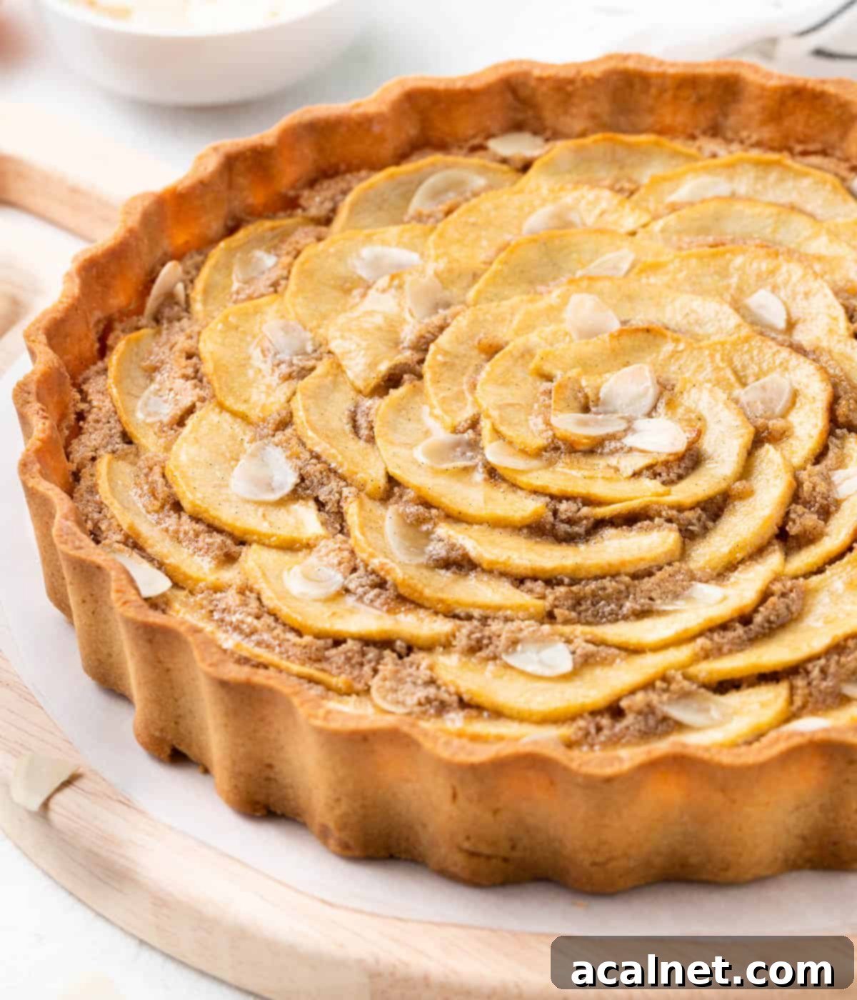 Elegant Apple Frangipane Tart 9 A side view of a baked Apple Frangipane Tart on a wooden board, showcasing its golden crust, plump almond filling, and artfully arranged, tender apple slices.