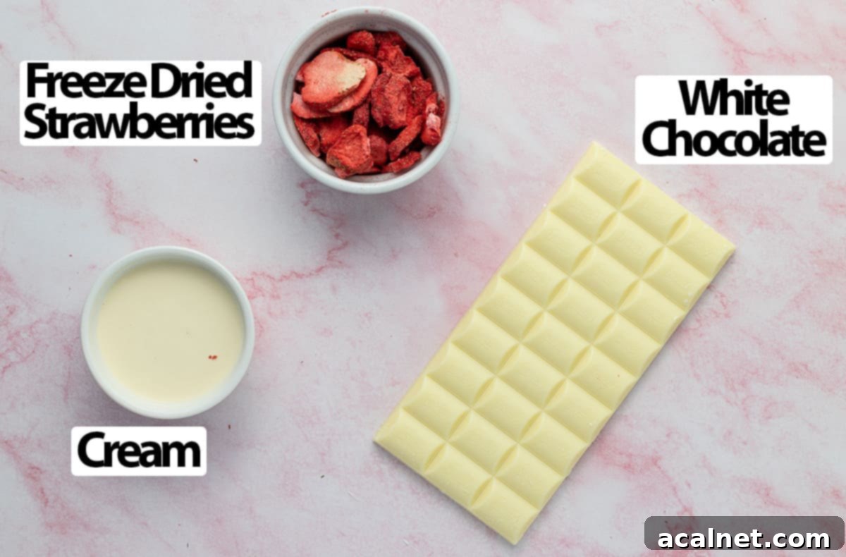 Three core ingredients: white chocolate, heavy cream, and freeze-dried strawberries, artfully arranged on a pink marbled surface.