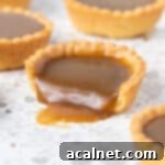 Close up on a tart bite a bite taken off and butterscotch sauce pouring out.