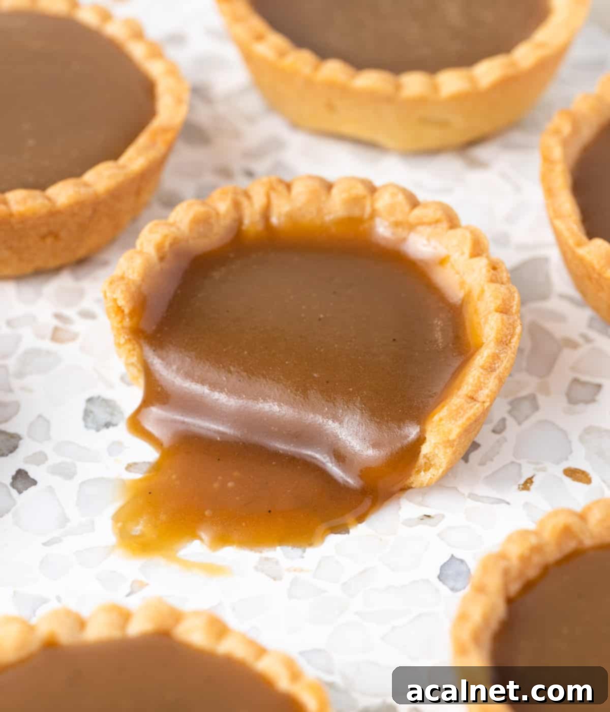 Butterscotch sauce oozing out of a tart cut in half.