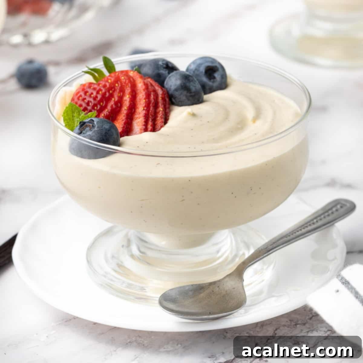 Effortless Vanilla Mousse Delights 2 Vanilla mousse in a glass dessert cup placed over a small white plate and topped with fresh berries.