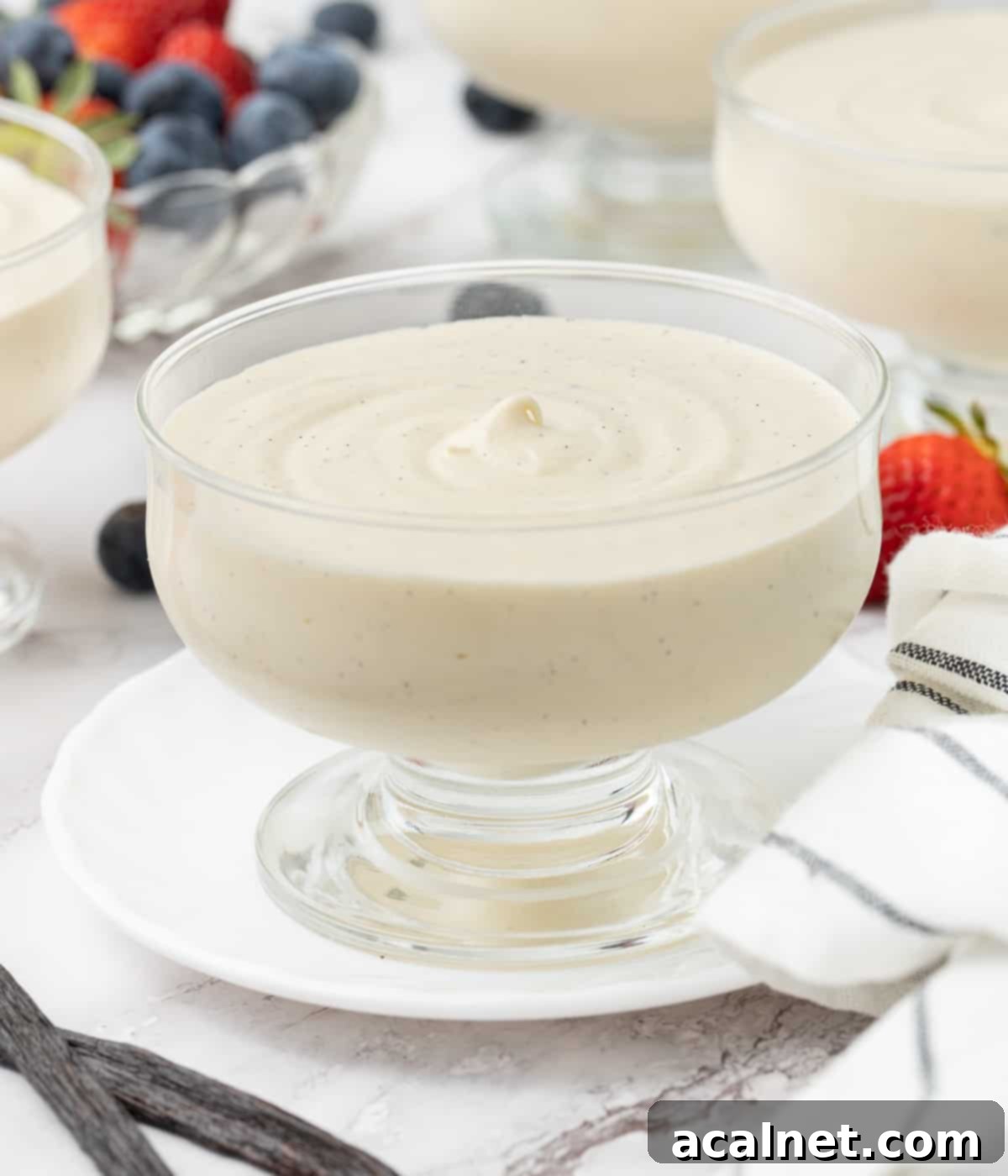 Effortless Vanilla Mousse Delights 6 Mousse in a glass cup with 3 mousses and a bowl of berries in the background.