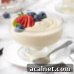 Effortless Vanilla Mousse Delights 9 Vanilla mousse in a glass dessert cup placed over a small white plate and topped with fresh berries.