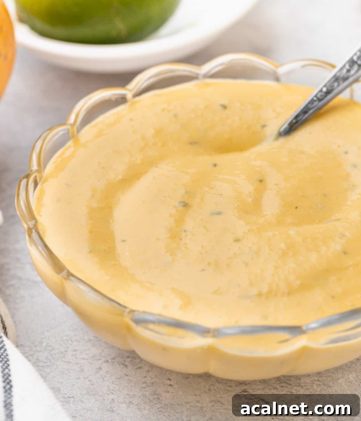 Curd in a glass bowl with a silver spoon dipped in.