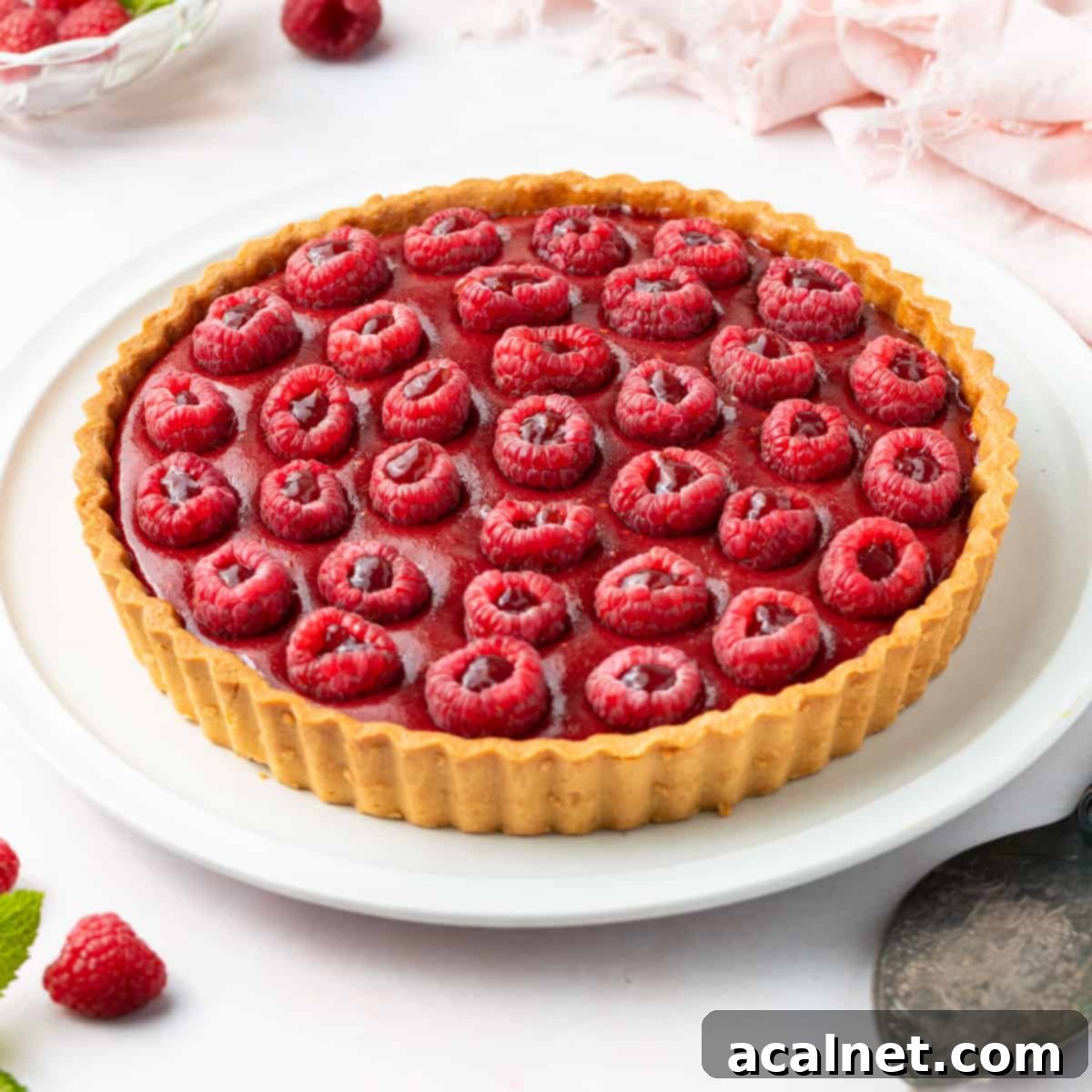 Finished tart placed on a large white plate over a white surface.