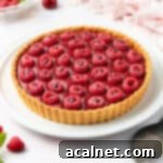 Finished tart placed on a large white plate over a white surface.