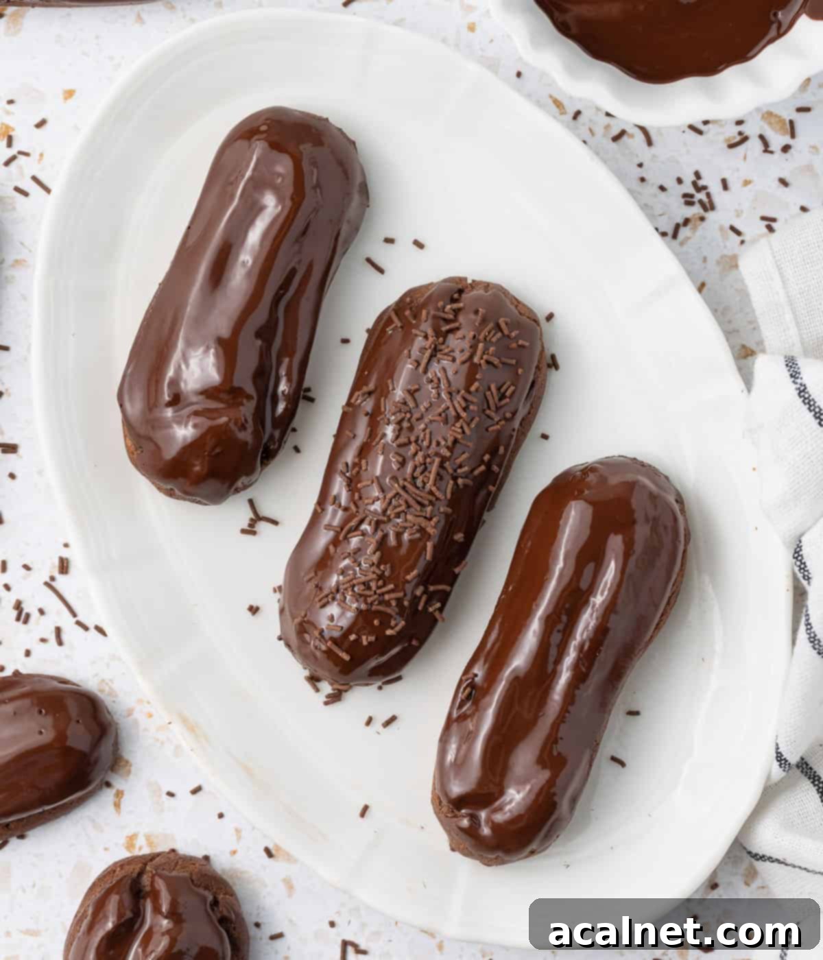 Three eclairs on a white oval plate seen from above.