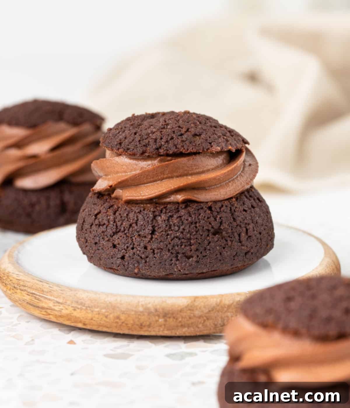 One choux placed on a small white and wooden coaster surrounded by two more choux.