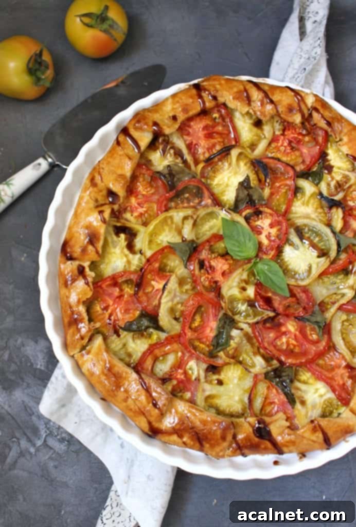 Half of the baked tomato galette from above, drizzled with balsamic reduction, on a white board