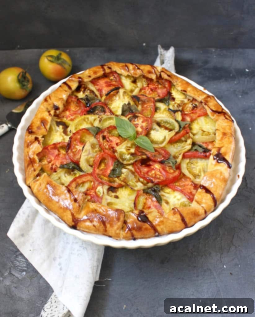 Side view on the baked tomato galette on a white cake stand with fresh basil