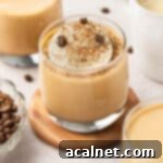 Glass cup of panna cotta on a small wooden coaster.