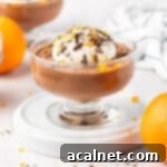 Mousse cup on a white plate surrounded by oranges.