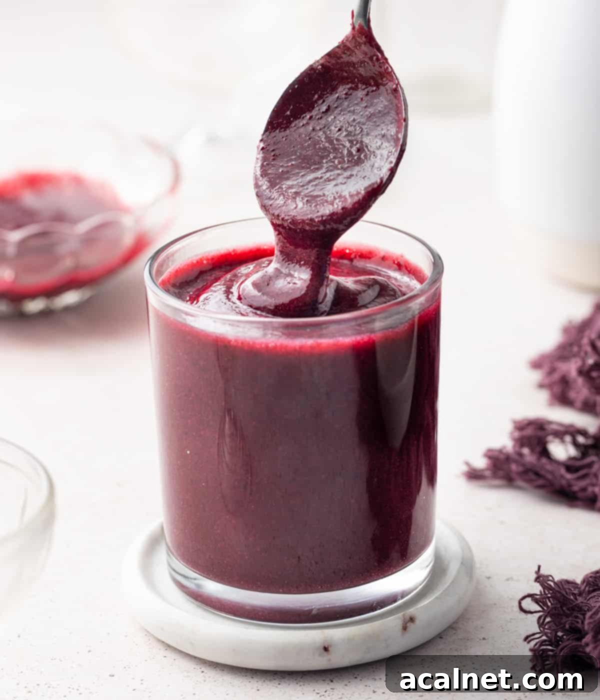 Coulis dripping from a spoon into a glass cup.