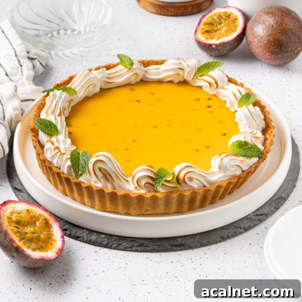 A stunning French Passion Fruit Tart resting on a large white plate, beautifully garnished with fresh passion fruits around its base. The vibrant yellow filling and crisp crust promise a delightful culinary experience.