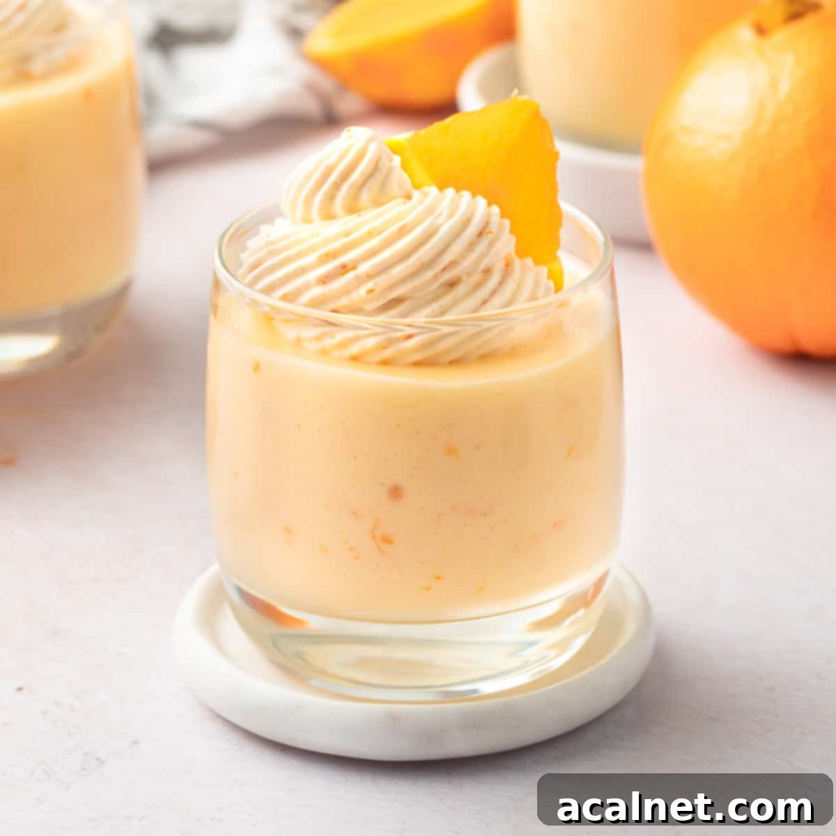 Zesty Orange Mousse Cups 2 Mousse cup on a marble coaster over a light orange background.