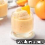 Zesty Orange Mousse Cups 10 Mousse cup on a marble coaster over a light orange background.