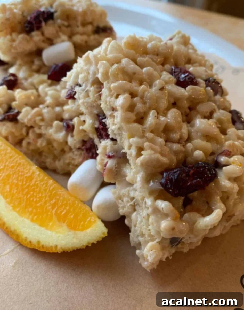 Stacked Fancy Rice Krispy Treats with a fresh orange wedge on the side, highlighting the orange creamsicle flavor.