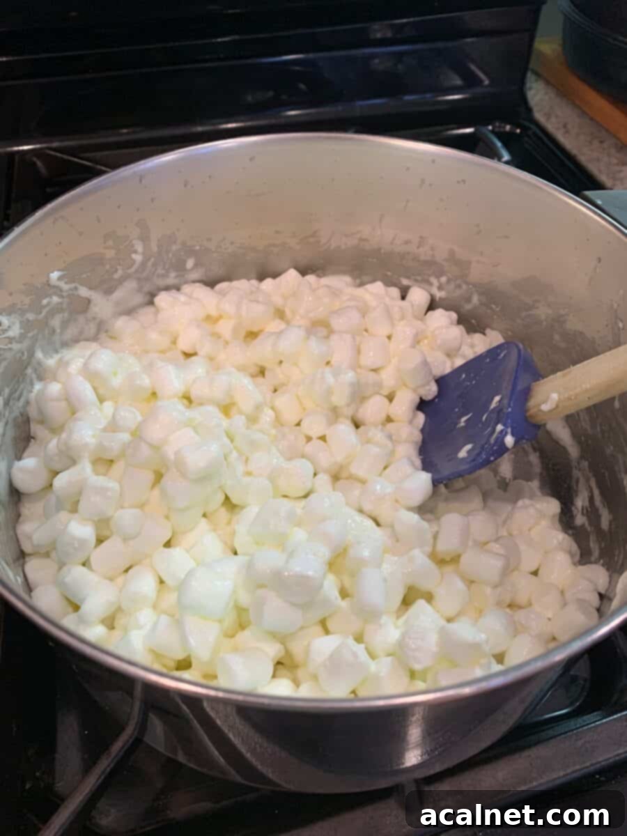 Mini-marshmallows and butter gently melting together in a saucepan on the stove over low heat.