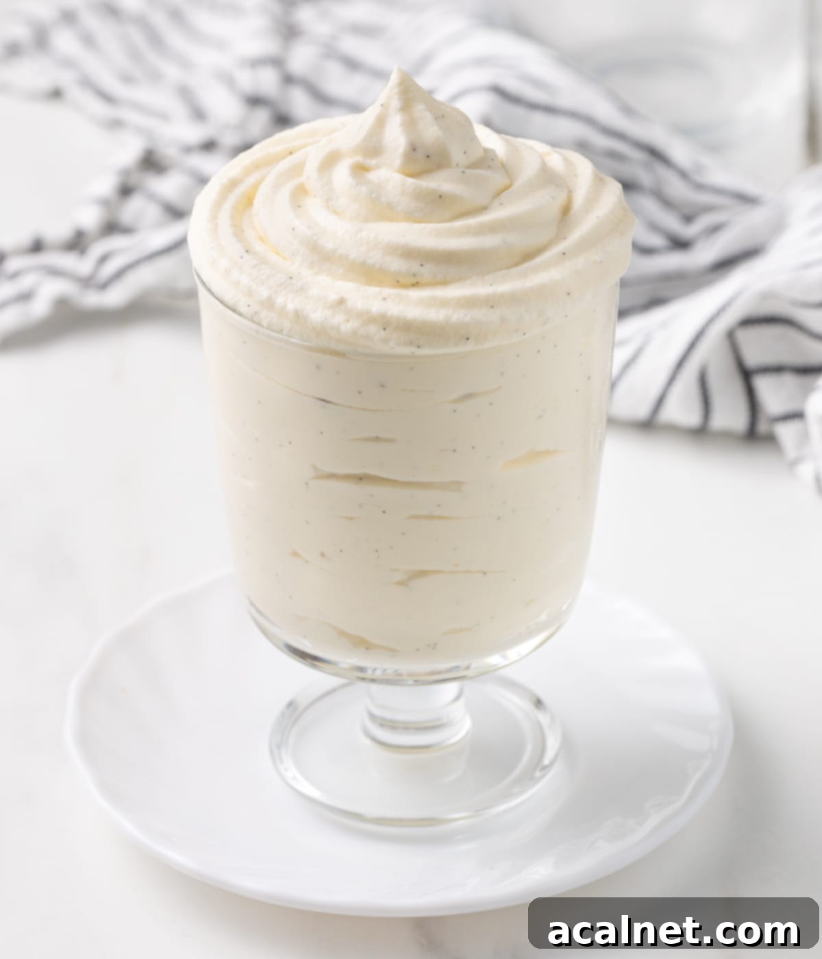 Close up on the chantilly cream piped inside a cup over a small white plate, showing its beautiful texture.