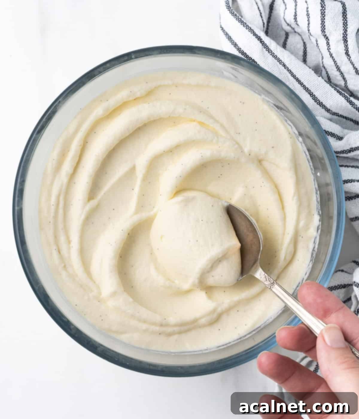 Cream in a large mixing bowl with a silver spoon, seen from above, illustrating the base for Chantilly Cream.