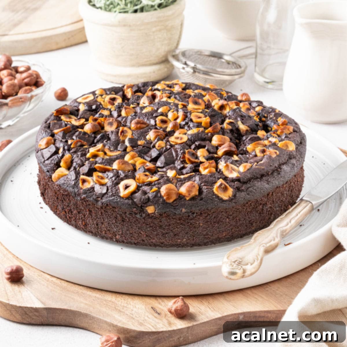 Simple Chocolate Hazelnut Delight 2 A beautifully presented slice of Chocolate Hazelnut Cake on a large white plate, elegantly placed over a rustic wooden cutting board, ready to be enjoyed.