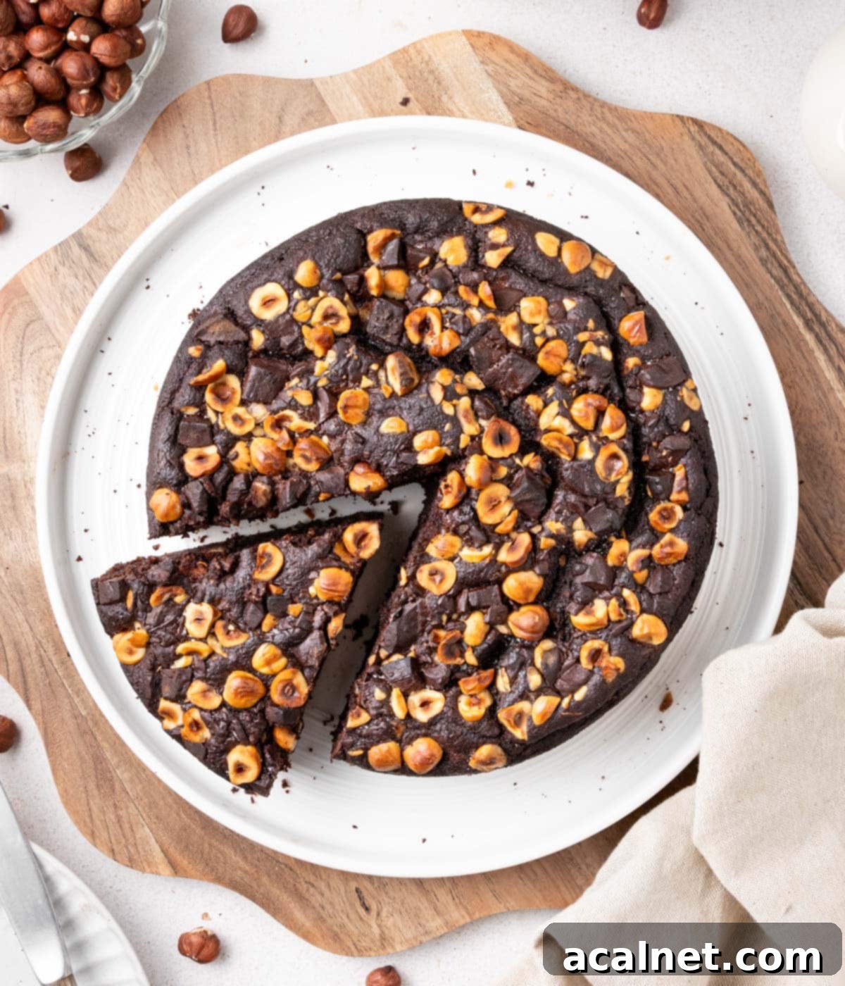 Simple Chocolate Hazelnut Delight 7 Another beautiful shot of the Chocolate Hazelnut Cake, with a slice removed, resting on a white plate atop a wooden board. The light highlights its moist crumb and inviting texture.