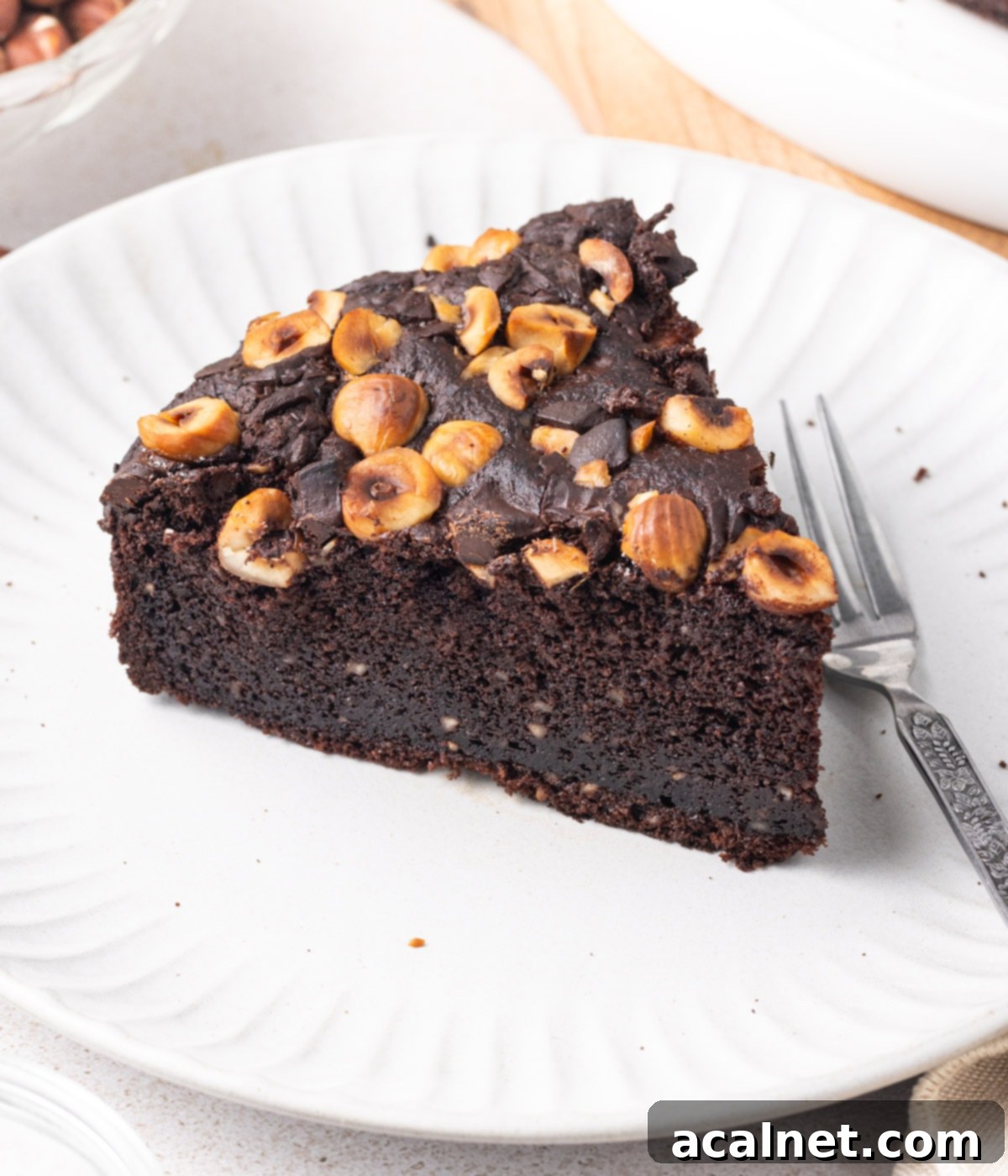 Simple Chocolate Hazelnut Delight 9 A close-up shot of a single, delectable slice of Chocolate Hazelnut Cake, presented on a small white plate, highlighting its rich texture and inviting appeal.