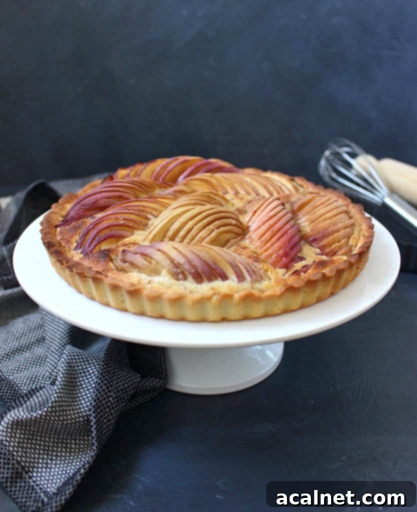 Tart on a white cake stand against a black surface.