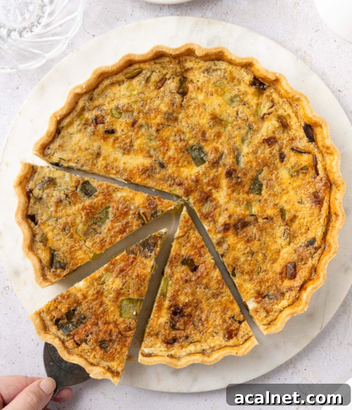 Picking up a slice of quiche with a cake server - seen from above, showcasing the golden crust and creamy filling.