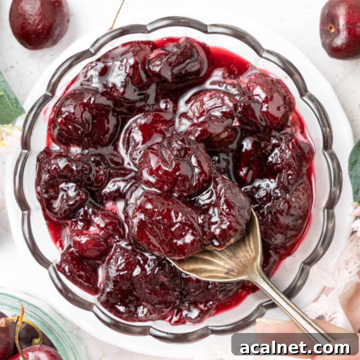 Picking up some compote from a glass bowl with a spoon, seen from above.