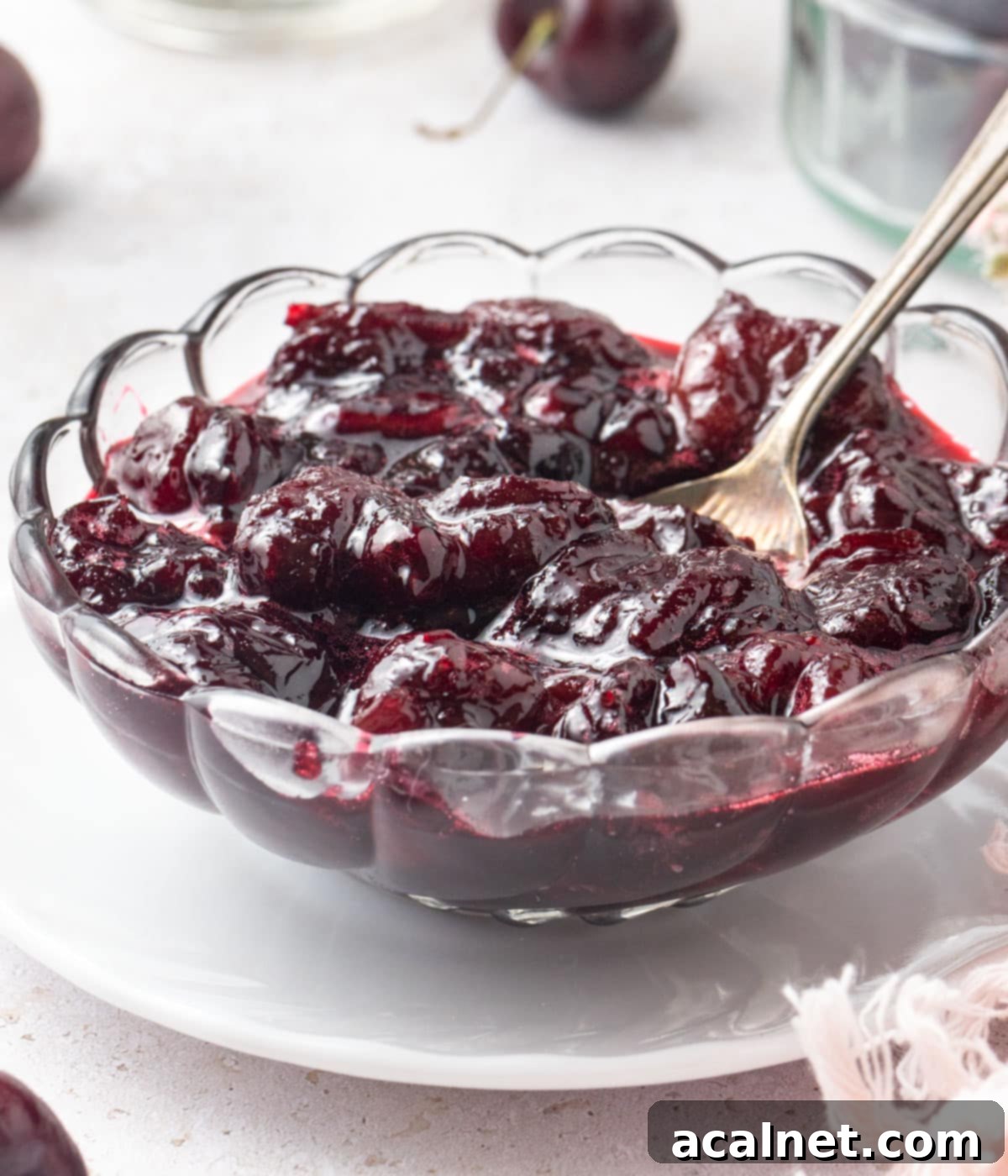 Compote in a small glass bowl with a silver spoon.