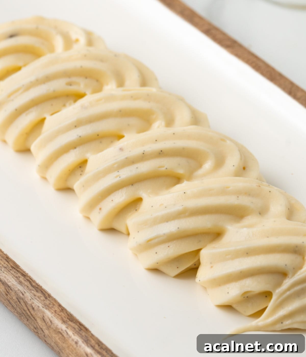 Side view on a row of piped cream over a white and wooden board.