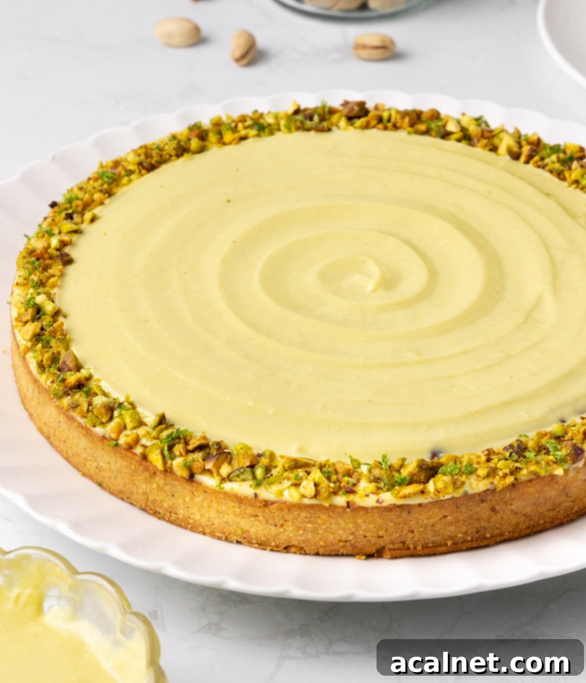 Close up on the side of the tart with the focus on the crust and crushed pistachio topping.