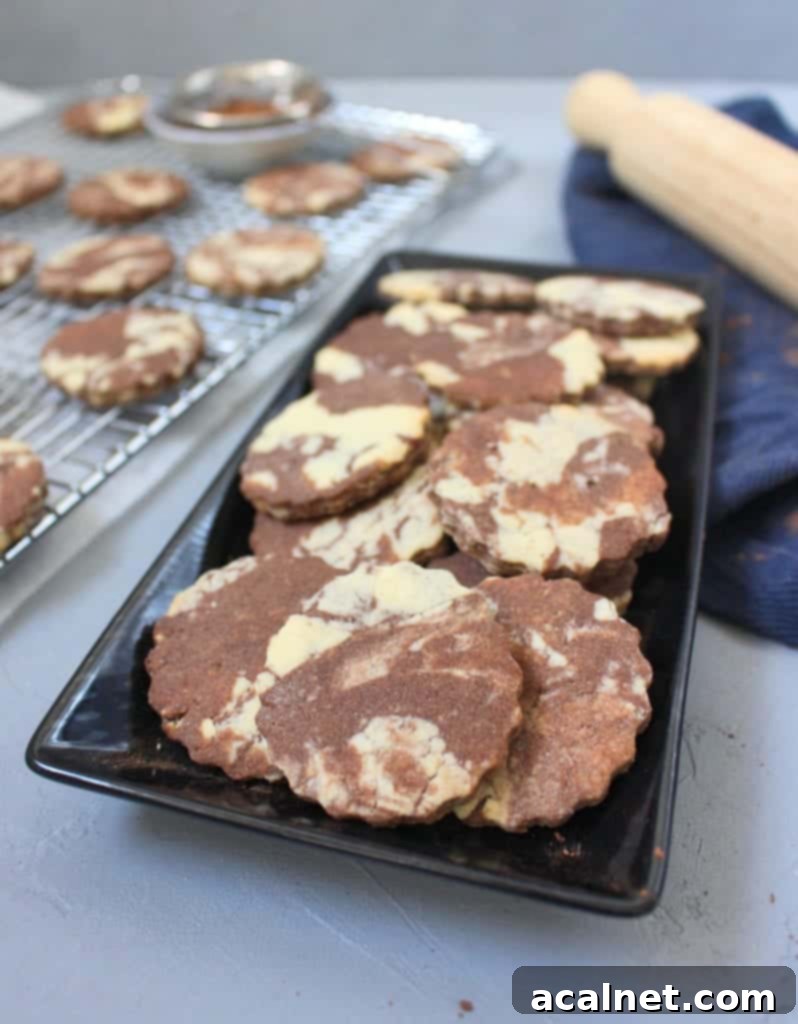 Cookies on a black plate with more chocolate vanilla marble cookies cooling on a cooling rack in the background.