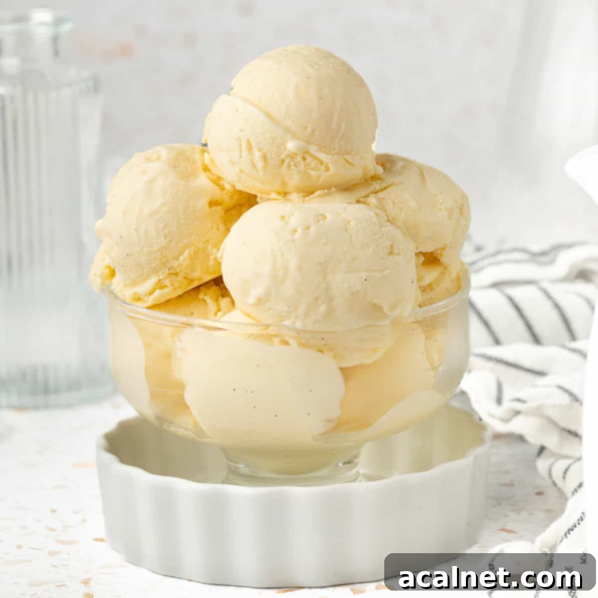 Ice Cream in a dessert cup inside a small white dish with striped napkin in the background.