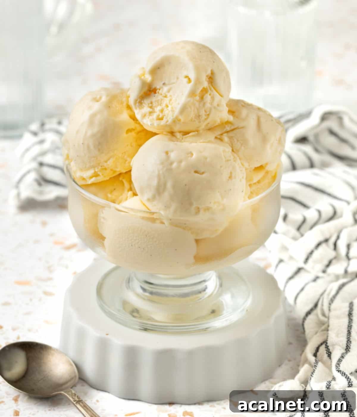 Scoops of ice creams stacked in a dessert cup placed over a small white dish.