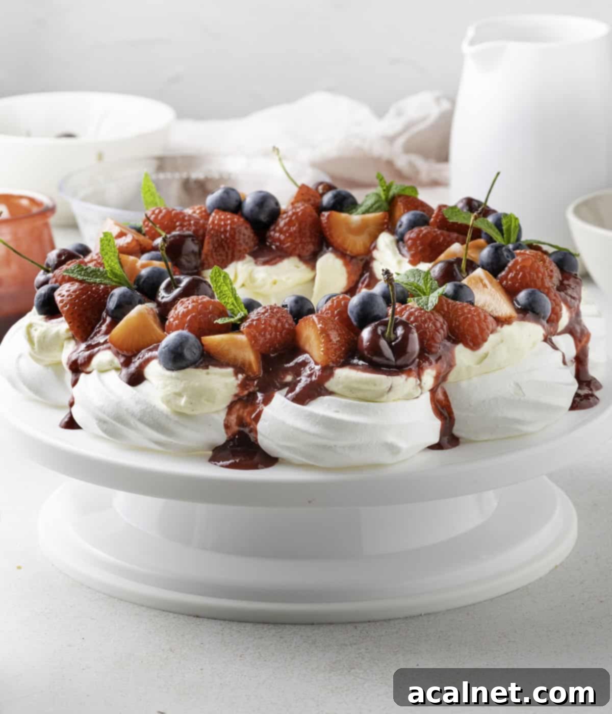 Full view of the wreath topped with cream, coulis and fruits over a white cake stand.