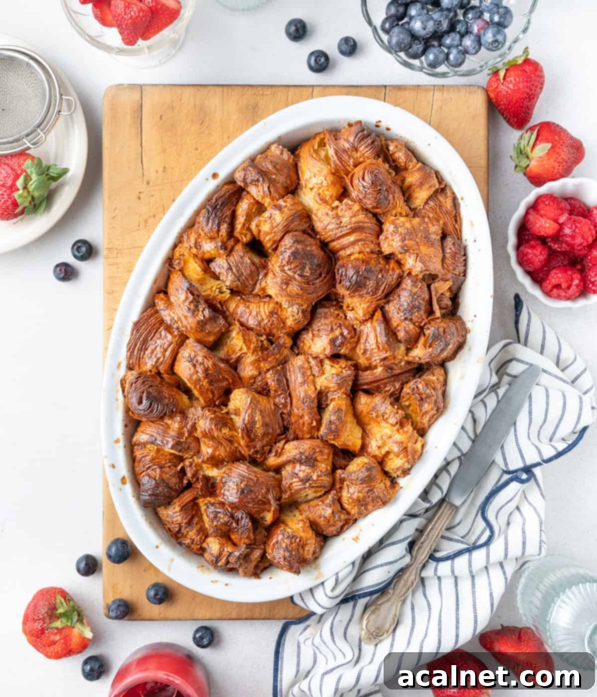 Baked dish in an oval white ceramic dish placed on a large wooden cutting board.