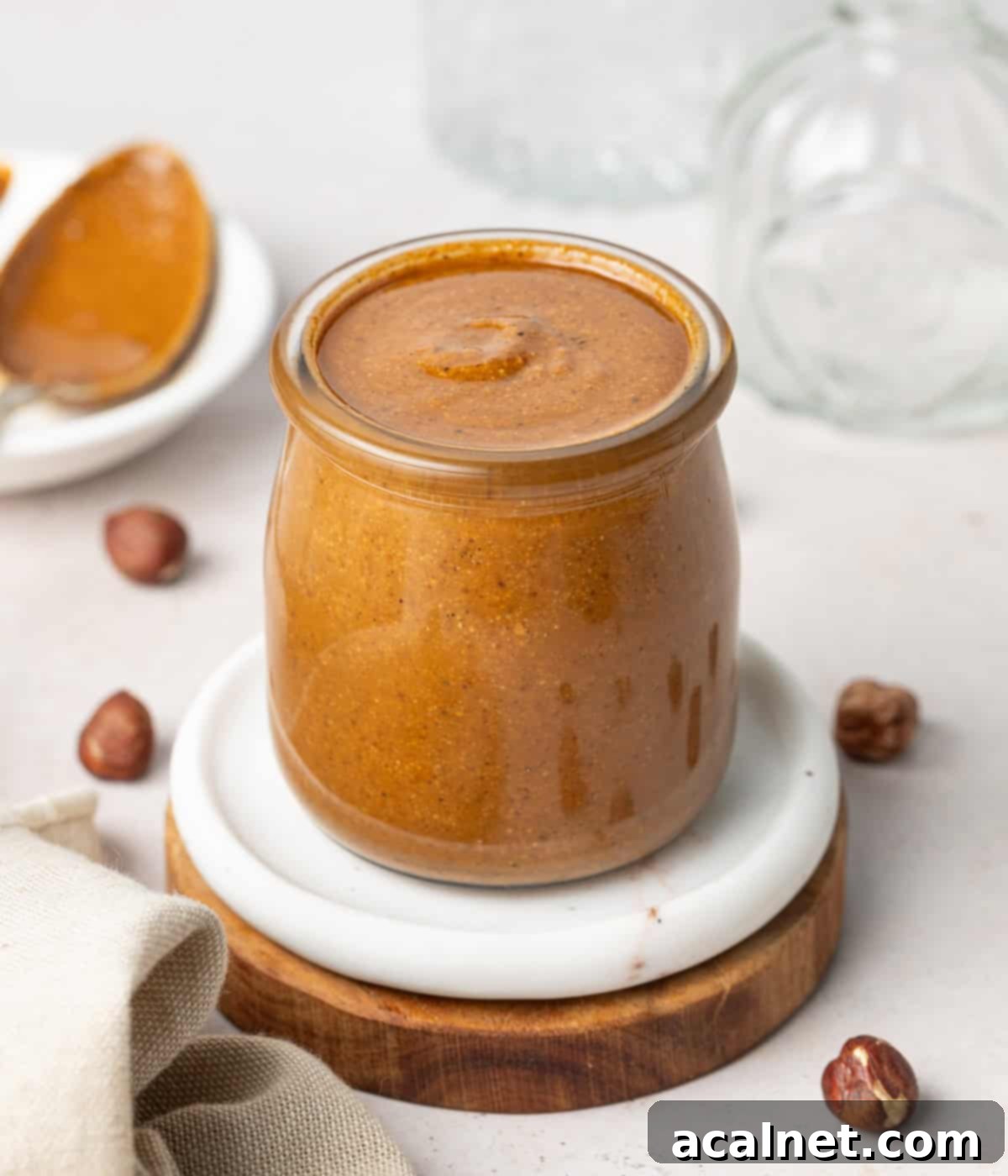 Crafting Homemade Hazelnut Butter 6 Hazelnut butter in a small glass jar over a white and a wooden coaster.