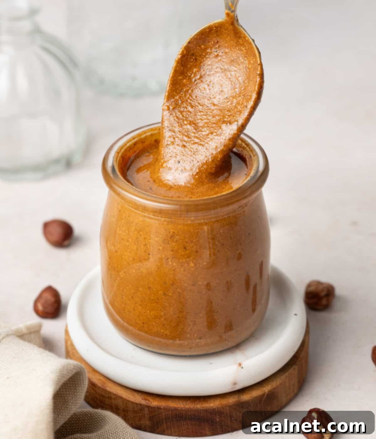 Crafting Homemade Hazelnut Butter 7 Spoon dipped in a glass jar filled with hazelnut paste.