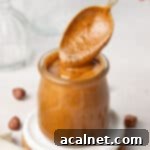 Crafting Homemade Hazelnut Butter 9 Silver spoon dipped in a small glass jar filled with hazelnut butter.