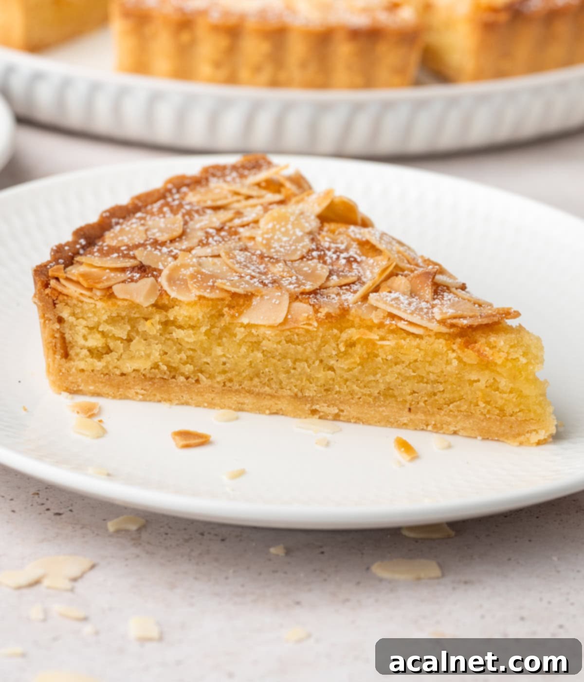 A perfectly portioned slice of French Almond Tart on a small dessert plate, ready to be savored.