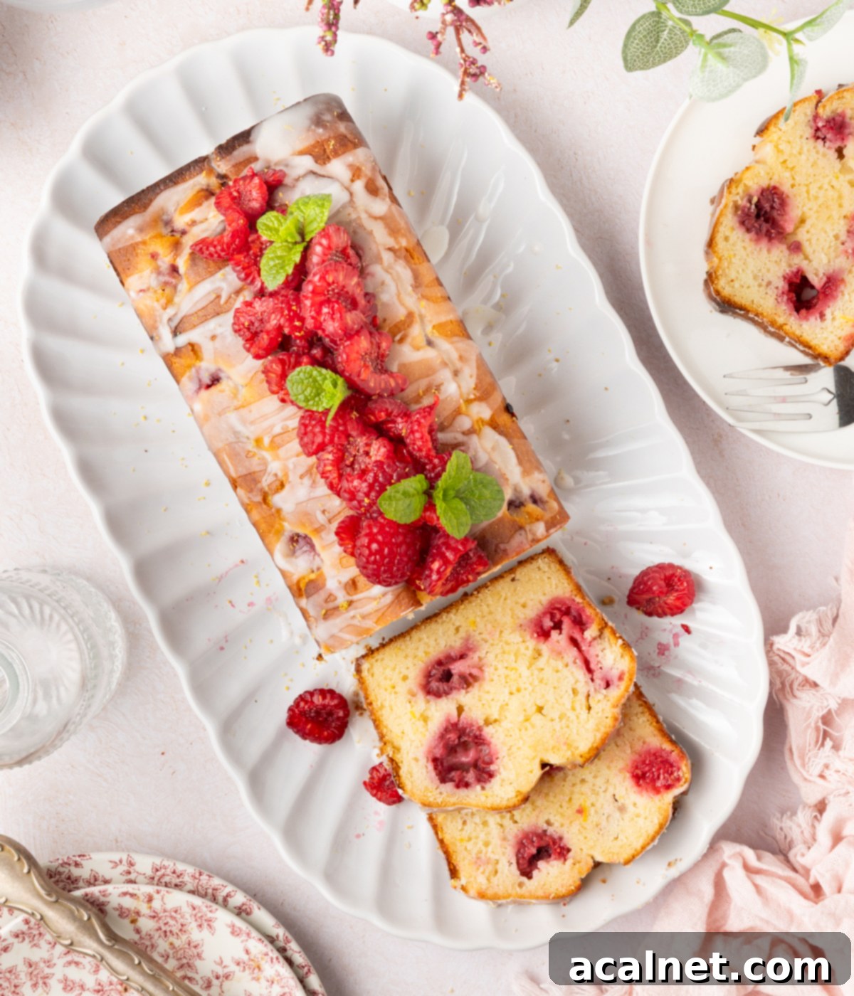 Zesty Lemon Raspberry Loaf 8 Cake on oval serving plate seen from above, with two slices laid on their side.